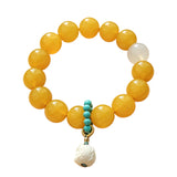 This handcrafted bracelet features glossy 14mm yellow agate beads paired with one white agate bead. It is accented with turquoise beads and finished with a detailed mammoth ivory guardian lion charm, bringing a warm vintage ethnic vibe.