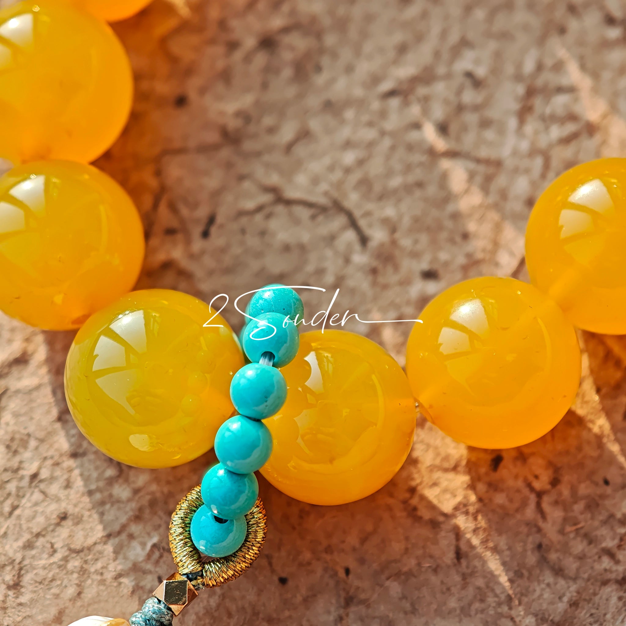 This handcrafted bracelet features glossy 14mm yellow agate beads paired with one white agate bead. It is accented with turquoise beads and finished with a detailed mammoth ivory guardian lion charm, bringing a warm vintage ethnic vibe.