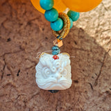 This handcrafted bracelet features glossy 14mm yellow agate beads paired with one white agate bead. It is accented with turquoise beads and finished with a detailed mammoth ivory guardian lion charm, bringing a warm vintage ethnic vibe.