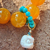 This handcrafted bracelet features glossy 14mm yellow agate beads paired with one white agate bead. It is accented with turquoise beads and finished with a detailed mammoth ivory guardian lion charm, bringing a warm vintage ethnic vibe.