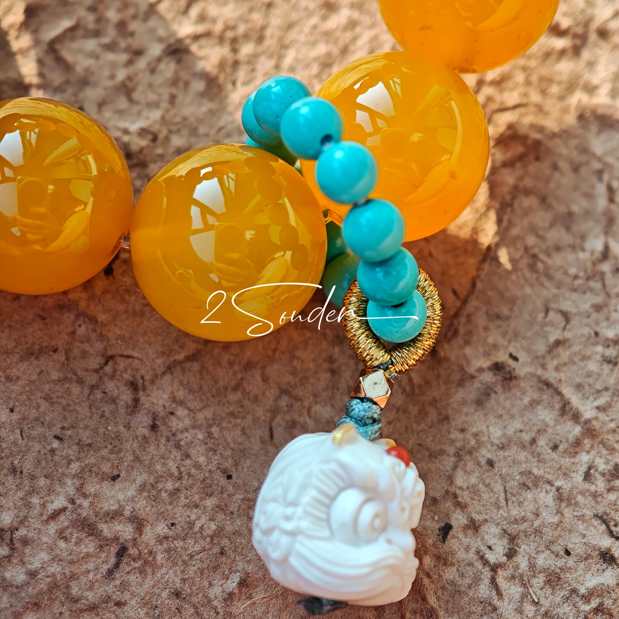 This handcrafted bracelet features glossy 14mm yellow agate beads paired with one white agate bead. It is accented with turquoise beads and finished with a detailed mammoth ivory guardian lion charm, bringing a warm vintage ethnic vibe.