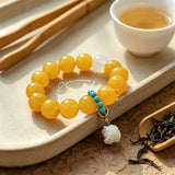 This handcrafted bracelet features glossy 14mm yellow agate beads paired with one white agate bead. It is accented with turquoise beads and finished with a detailed mammoth ivory guardian lion charm, bringing a warm vintage ethnic vibe.