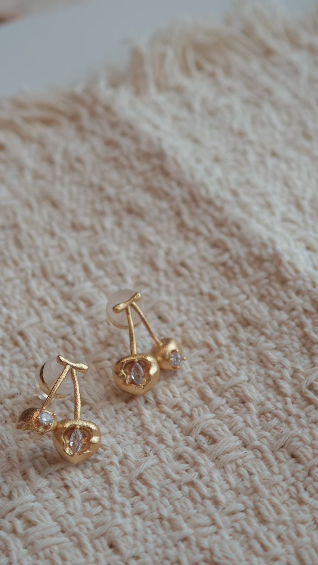 These cherry-shaped stud earrings feature a luxurious matte sandblasted finish, crafted from thick-plated real gold over 925 sterling silver posts. Each earring is designed as a pair of cherries, adorned with a marquise-cut and a round-cut sparkling clear stone, adding a delicate, eye-catching sparkle. The playful, organic cherry silhouette and premium gold plating make them a chic, elegant accessory for everyday wear.