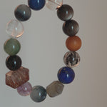 Cool lunar tones bloom from Black Gold Super Seven, Herkimer diamonds, clear quartz, sandalwood, amethyst, silver obsidian, white phantom quartz, and kyanite.